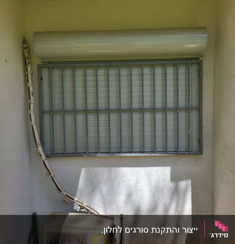סורגי מתכת על חלון עם תריס גלילה